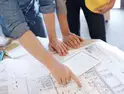 Bauleiter und Handwerker planen den Hausbau am Bauplan