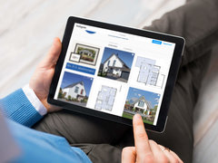 Mann am Tablet schaut sich das Instagram-Profil von Baumeister-Haus an